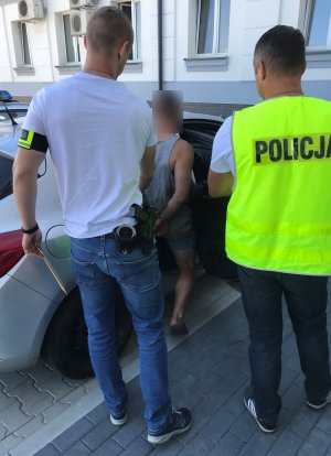 Policjanci WK doprowadzający zatrzymanego, który wsiada do samochodu
