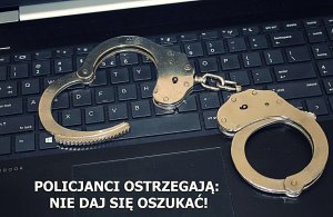 Kajdanki lezące na klawiaturze komputera. Napis: Policjanci ostrzegają: Nie daj się oszukać!