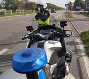 Policjant przy motocyklu sprawdza prędkość pojazdów.