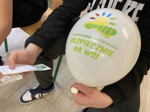 Chłopiec trzyma balona z napisem &quot;Ogólnopolski konkurs plastyczny dla dzieci Bezpiecznie na wsi&quot;