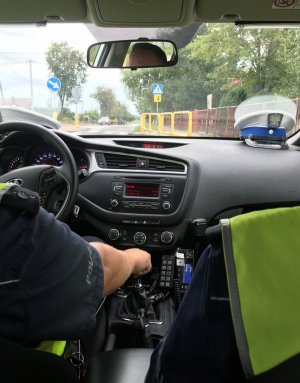 Policjanci WRD siedzący w radiowozie. Przed nimi znak &quot;przejście dla pieszych&quot;