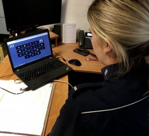 Policjantka siedzi przy biurku. Przed nią laptop.