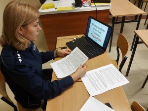 Policjantka siedzi przy stoliku. Przed nią laptop. Na ekranie laptopa napis 10 grudnia Międzynarodowy Dzień Praw Człowieka.