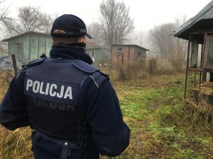 Policjant wydziału patrolowo - interwencyjnego. W tle opuszczone baraki.