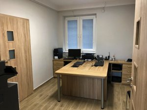 Wnętrze pomieszczenia, w którym stoją dwa biurka i sprzęt biurowy.