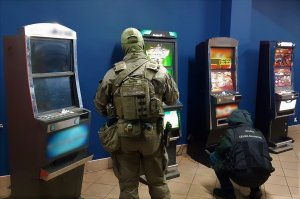 Funkcjonariusze KAS wewnątrz pomieszczenia, w którym stoją maszyny do gier hazardowych.