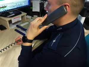 Policjant siedzi przy biurku. Rozmawia przez telefon.