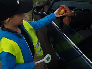 Chłopiec daje kierowcy jabłko.