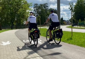 Policjant i policjantka na rowerach jadą ścieżką rowerową.