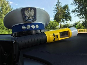 Urządzenie do badania stanu trzeźwości i czapka policjanta ruchu drogowego na podszybiu radiowozu.