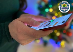Kobieta trzymająca w dłoniach telefon komórkowy. W tle choinka