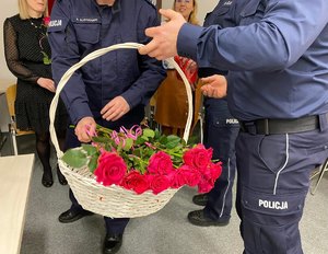 Policjant trzyma kosz z różowymi różami