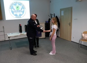 Komendant Powiatowy Policji w Kolnie wręcza dyplom dziewczynce.