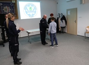 Komendant Powiatowy Policji w Kolnie wręcza dyplom chłopcu.
