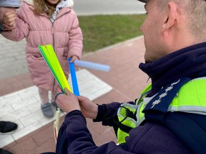Policjant daje dziecku opaskę odblaskową