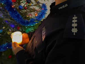 Policjant trzyma w dłoniach betlejemskie światełko pokoju