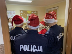 Policjanci w czapkach Mikołaja i Mikołaj wśród dzieci