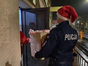 Policjant w czapce Mikołaja niesie prezenty