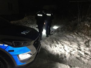 Policjanci idący nocą po śniegu