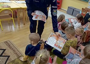 Policjanta w szkole rozdaje dzieciom laurki