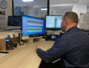 Policjant siedzący przed monitorami komputerów