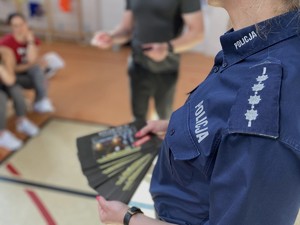 Policjantka trzyma w dłoni ulotki informacyjne