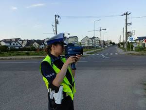 Policjantka za pomocą ręcznego miernika prędkości sprawdza prędkość pojazdów