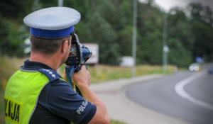 Policjant za pomocą ręcznego miernika prędkości mierzy prędkość pojazdów