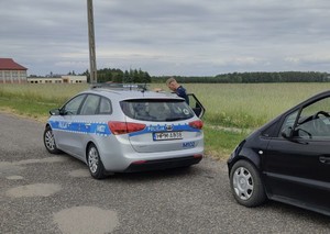 Samochód osobowy, radiowóz i policjant na drodze