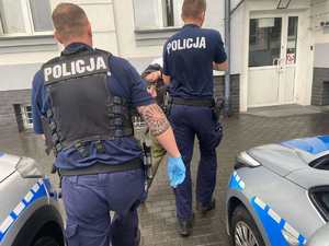 Policjanci prowadzą zatrzymanego mężczyznę