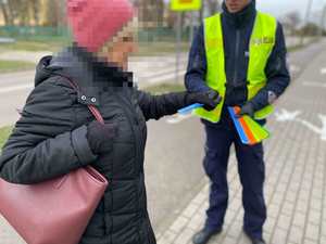 Policjant daje kobiecie opaskę odblaskową