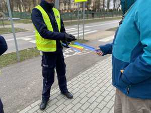 Policjant daje mężczyźnie opaskę odblaskową