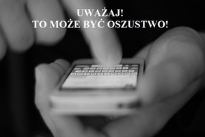 Telefon komórkowy trzymany w dłoniach. Napis: Uważaj! To może być oszustwo!