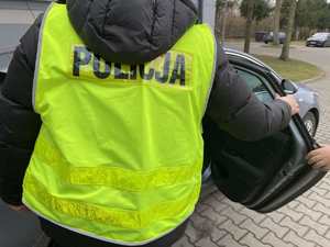 Nieumundurowany policjant w kamizelce odblaskowej z napisem POLICJA