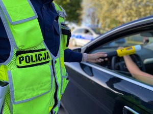 Policjant przeprowadza kontrole stanu trzeźwości kierowcy osobówki
