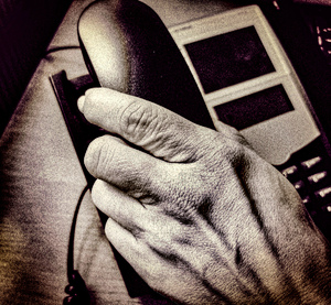 dłoń podnosząca słuchawkę telefonu stacjonarnego