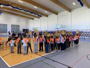 Dzieci ubrane w kamizelki odblaskowe na hali sportowej