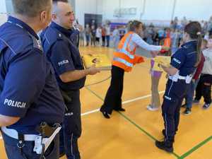 Policjanci w szkole rozdają elementy odblaskowe