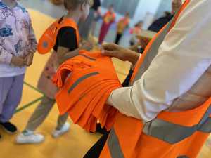 Kobieta rozdaje kamizelki odblaskowe