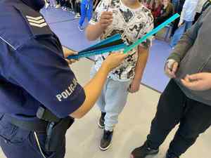 Policjanci w szkole rozdają elementy odblaskowe