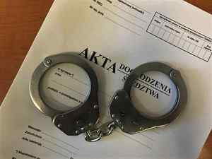 Okładka akt dochodzenia/śledztwa na niej leżą kajdanki