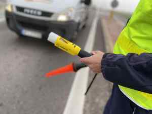 Policjant z latarką do zatrzymywania pojazdów i alkomatem