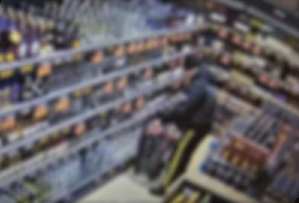 Zrzut ekranu ze sklepowego monitoringu. Mężczyzna przy półkach z alkoholem.