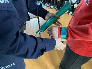 Policjantka zakłada opaskę odblaskową chłopcu na rękę