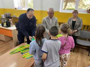 Policjant rozdaje opaski odblaskowe dzieciom