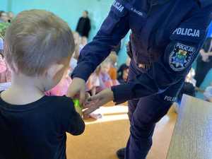 Policjantka zakłada opaskę odblaskową dziecku