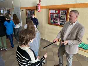 Policjantka i mężczyzna rozdają opaski odblaskowe w szkole