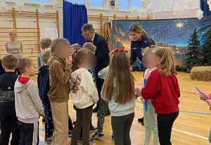 Policjantka rozdaje w szkole odblaski dzieciom