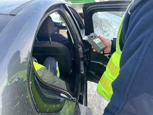 Policjant sprawdza stan trzeźwości kierowcy, który siedzi na tylnym siedzeniu w radiowozie