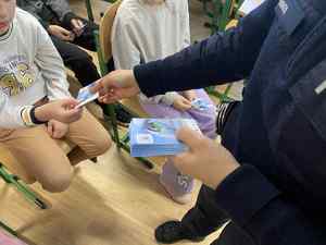 Policjantka rozdaje w szkole ulotki informacyjne